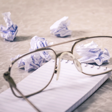 Glasses, notebook, paper balls | Should You Write in First, Second, or Third Person on Your Therapist Website? | Brighter Vision Web Solutions | Marketing Blog for Therapists