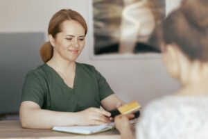 Healthcare time. happy massage therapist woman in massage cabinet with client accepting credit card payments via terminal on reception.