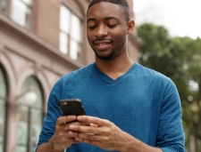 Man in Blue Sweater Texting on Phone